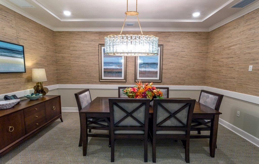 A well-decorated dining room featuring a stylish chandelier, a rectangular table with chairs, and wall artwork.