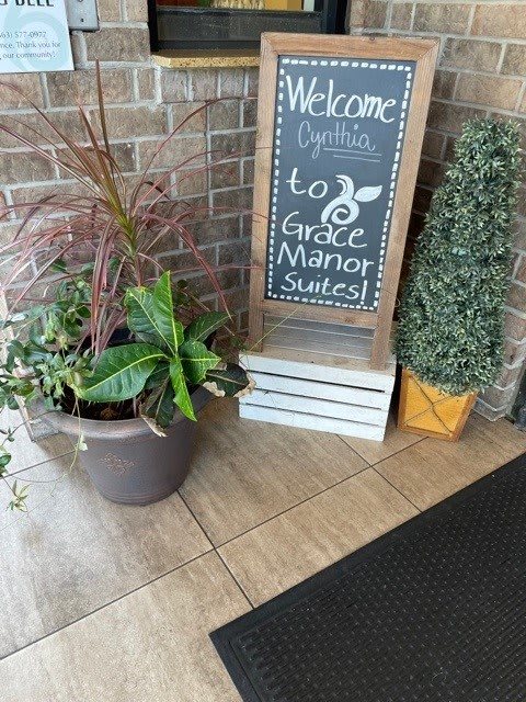 A welcoming entrance with a chalkboard sign and potted plants at Circle Manor Suites.