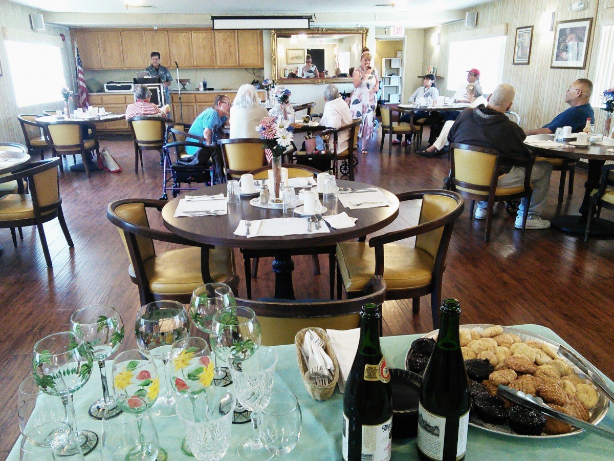 A cozy dining area with several tables set for guests, featuring wine bottles and glasses in the foreground.