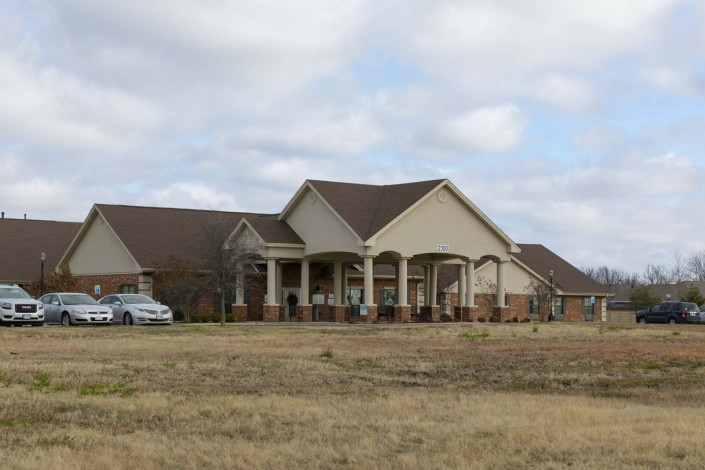 A large suburban house with a spacious front lawn under a cloudy sky.