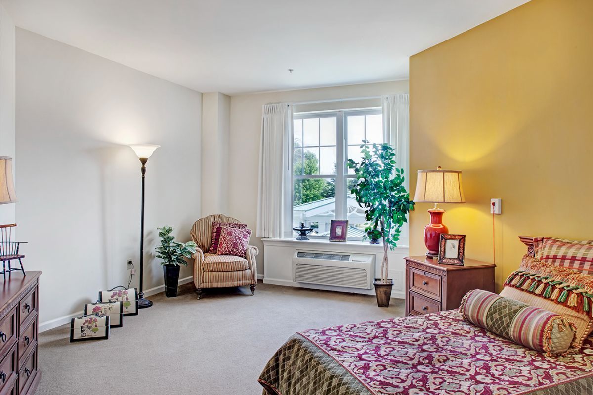A cozy bedroom with a large window, colorful decor, and comfortable furniture.