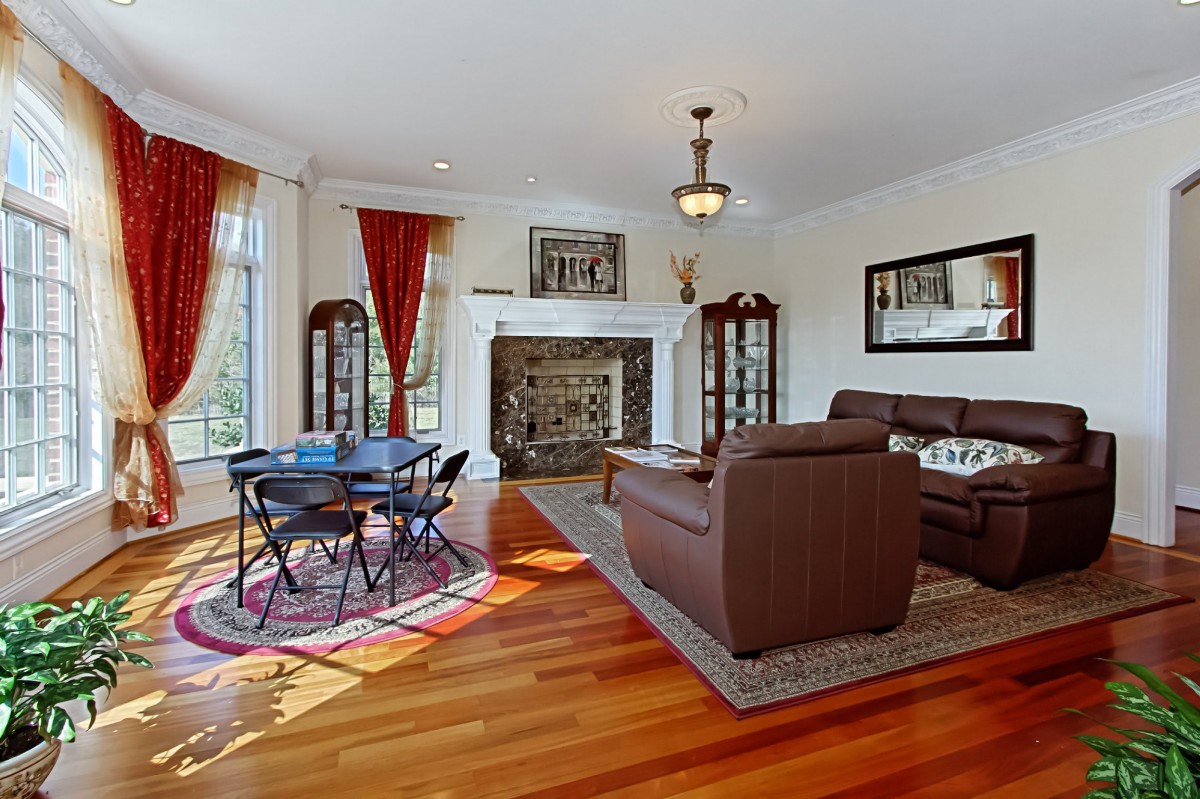 A spacious living room with a fireplace, brown sofas, and a small dining area on wooden flooring.