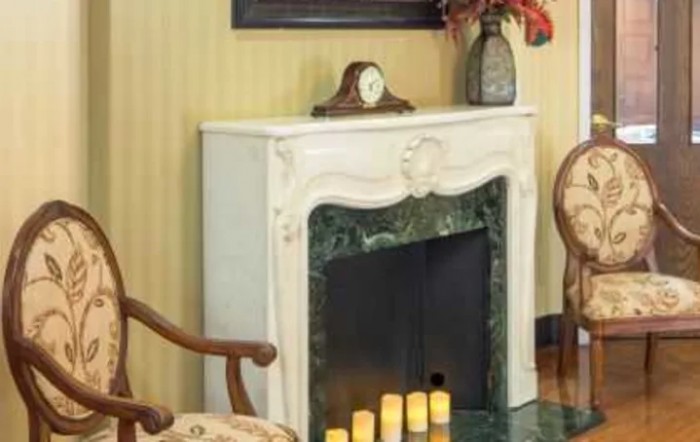 A decorated fireplace with a clock, vase, and candles on the mantel.