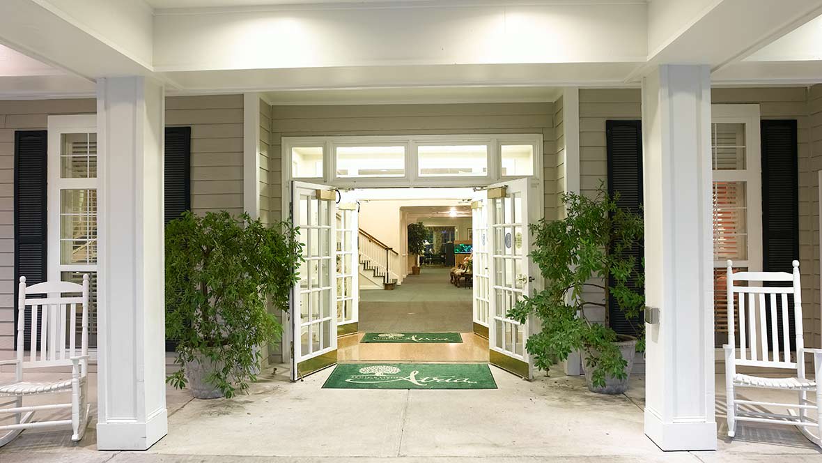 A welcoming entrance with open double doors and potted plants on either side.