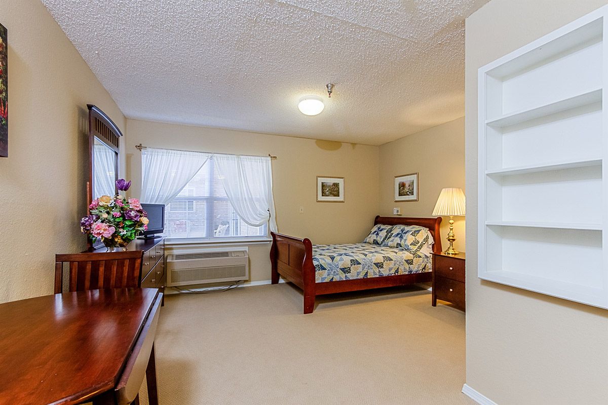 A cozy bedroom with a wooden bed, floral bedding, and natural lighting.