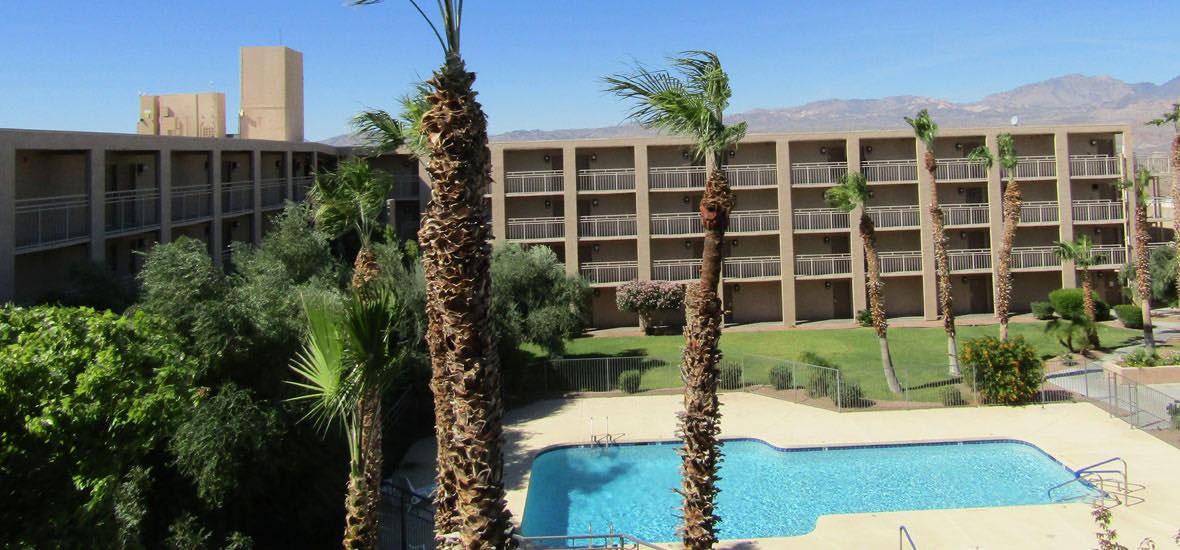 A hotel with a swimming pool surrounded by palm trees.