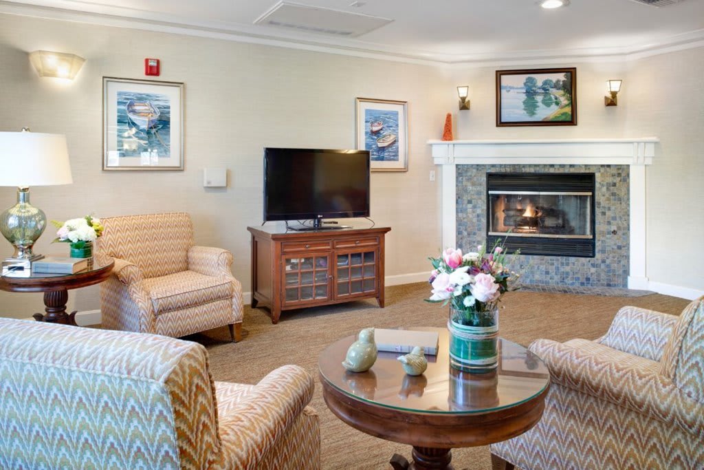 A cozy living room featuring a fireplace, television, and comfortable seating with decorative art on the walls.