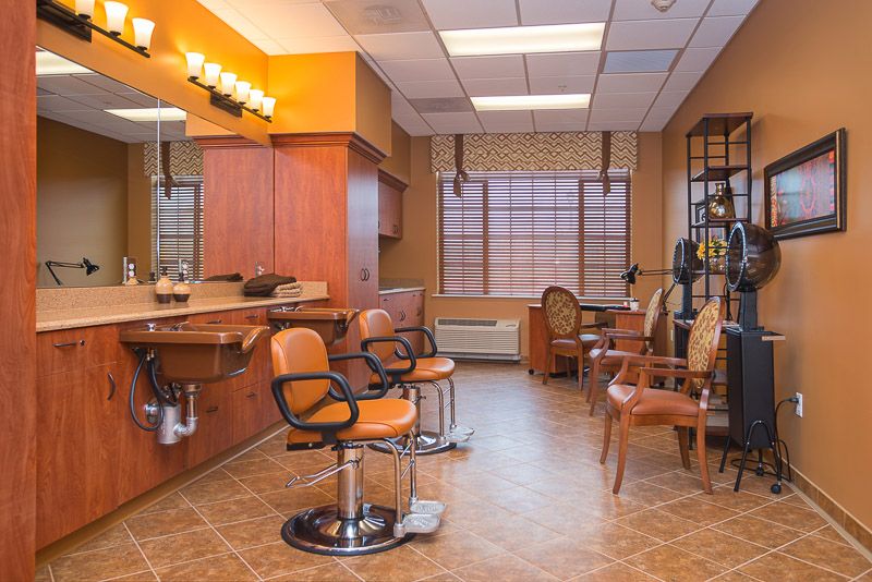 A cozy hair salon interior with orange and brown tones, featuring barber chairs, mirrors, and wooden furniture.