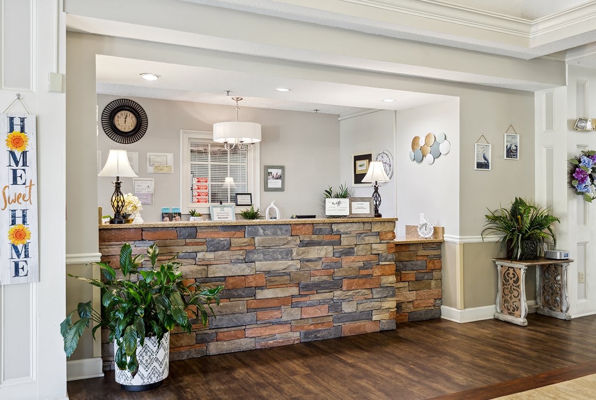A welcoming reception area featuring a stone-accented desk, elegant decor, and warm wood flooring.