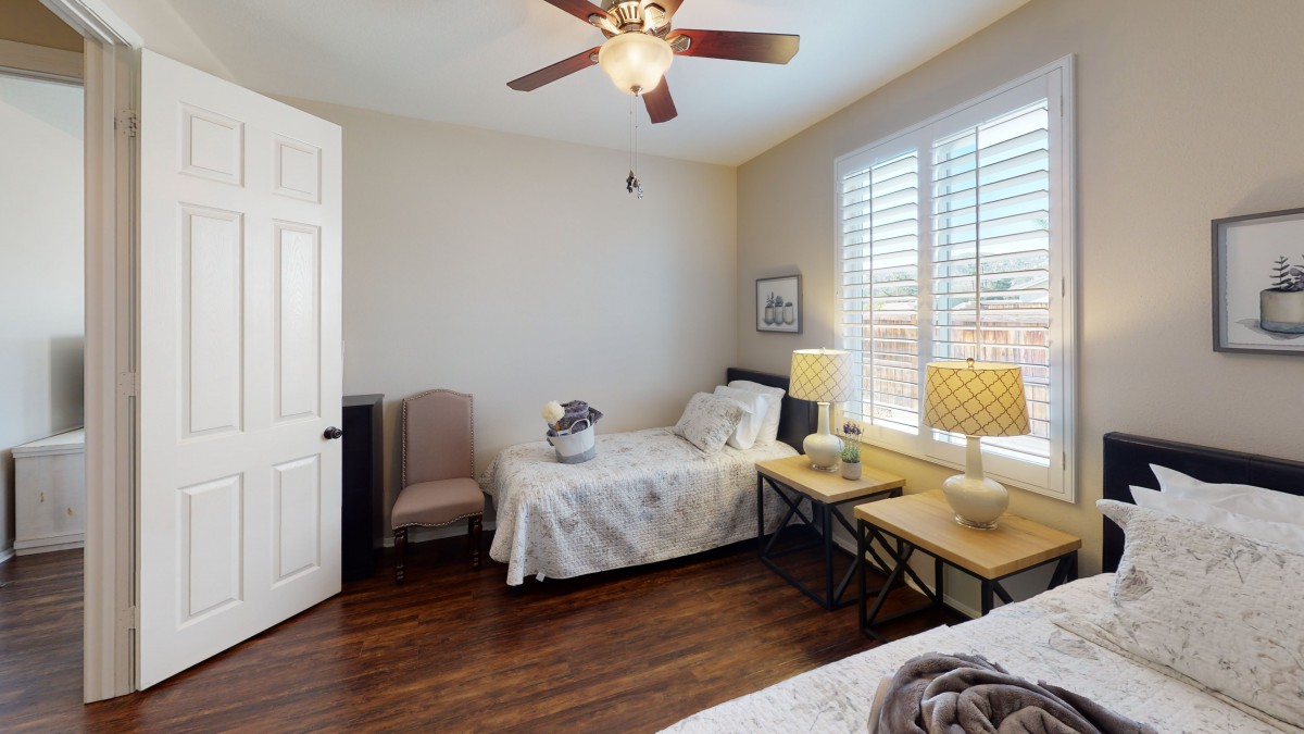 A cozy bedroom with a single bed, nightstand, and ceiling fan.