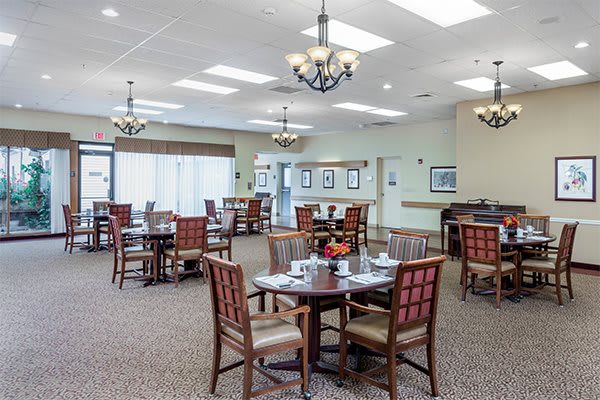 Spacious dining area with wooden tables and chairs, adorned with chandeliers.