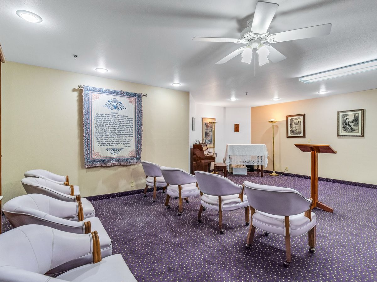 A small chapel interior with arranged chairs, a pulpit, and an altar in a cozy setting.