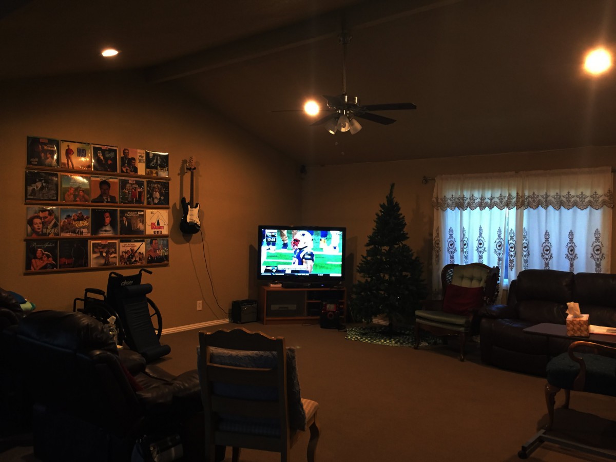 A cozy living room with a TV, guitar on the wall, and holiday decorations.