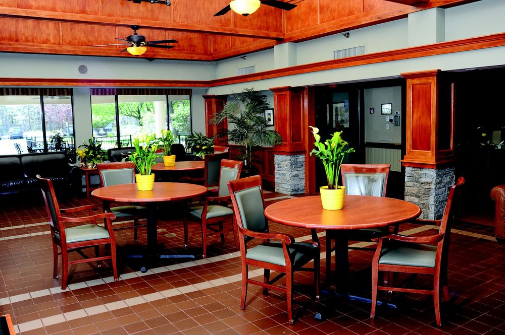 A cozy dining area with wooden tables and chairs, decorated with green plants.