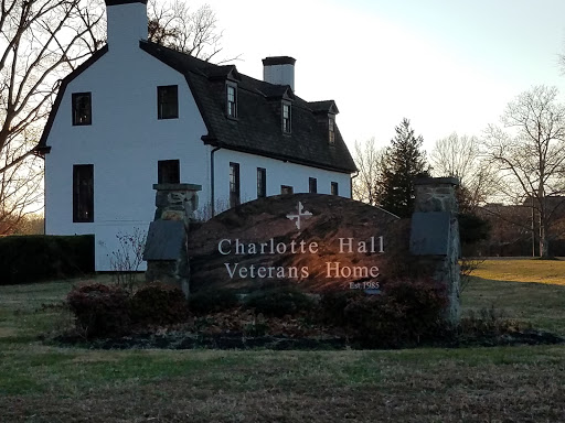 The entrance sign of the Charlotte Hall Veterans Home, set against a backdrop of a historical building.