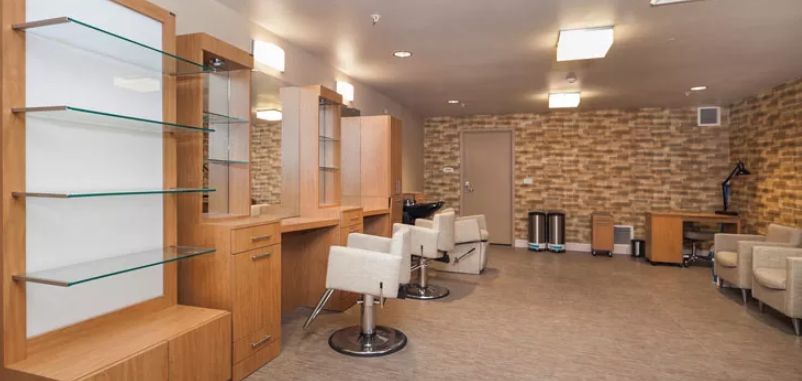 A modern hair salon interior featuring stylish chairs and mirrors against a brick wall.