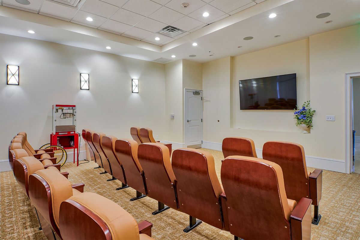A small indoor theater with rows of comfortable seating facing a large screen.