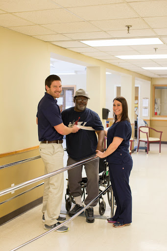 Healthcare professionals assisting a patient in rehabilitation.