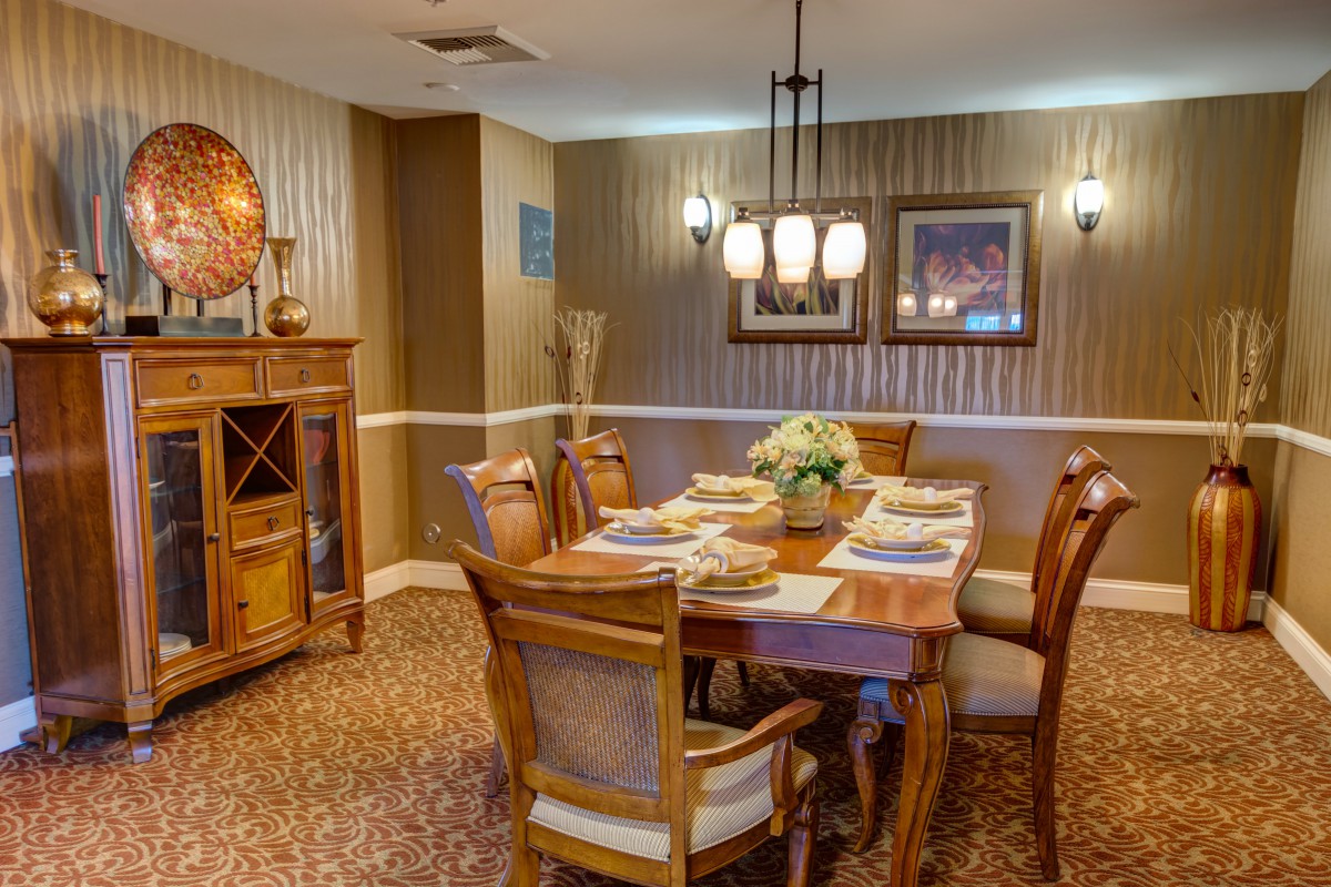 A warmly decorated dining room with wooden furniture and a chandelier, featuring a set dining table.
