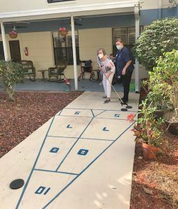 Two people playing shuffleboard outdoors.