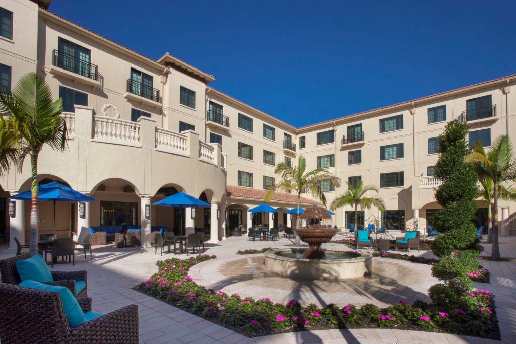 A luxurious hotel courtyard featuring a central fountain and surrounded by elegant architecture.
