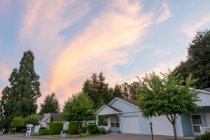 A suburban house surrounded by trees and illuminated by a colorful sunset sky.