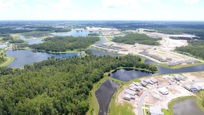 Aerial view of a landscape featuring forests, lakes, and suburban development.