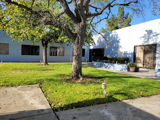 A peaceful outdoor view featuring a building surrounded by green grass and a prominent tree.