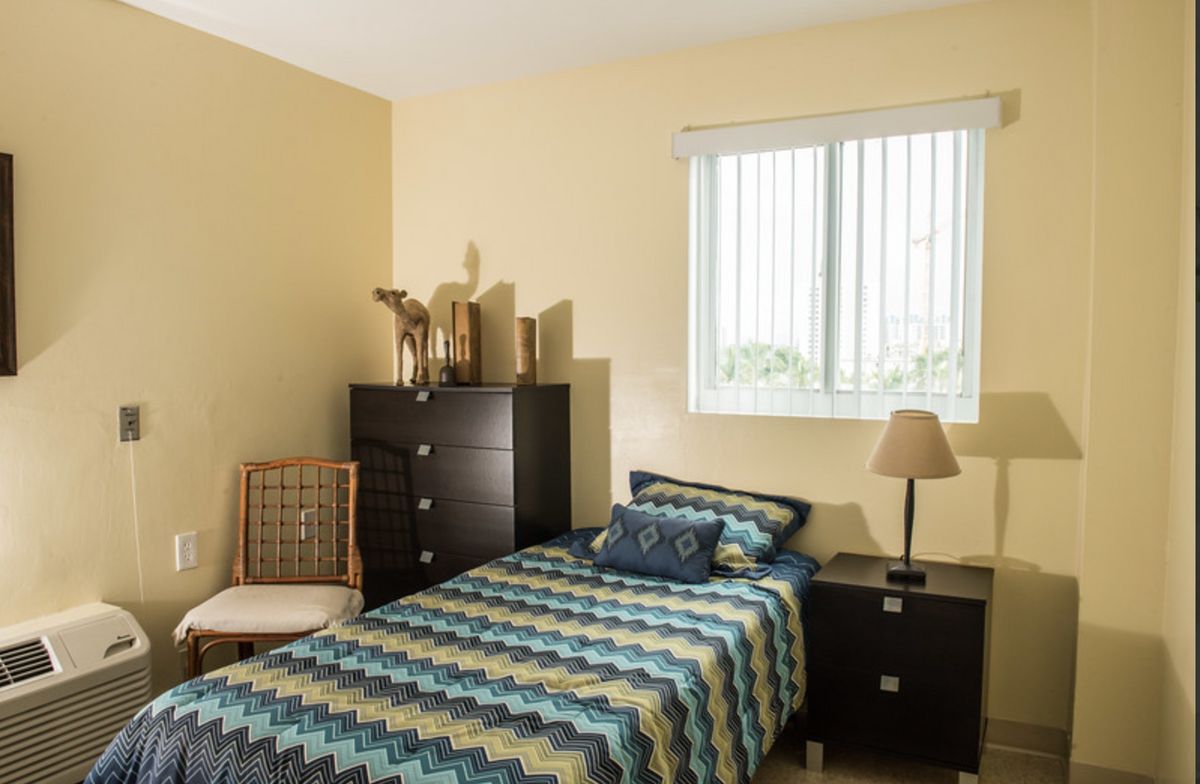 A cozy bedroom with a single bed, dresser, and window.