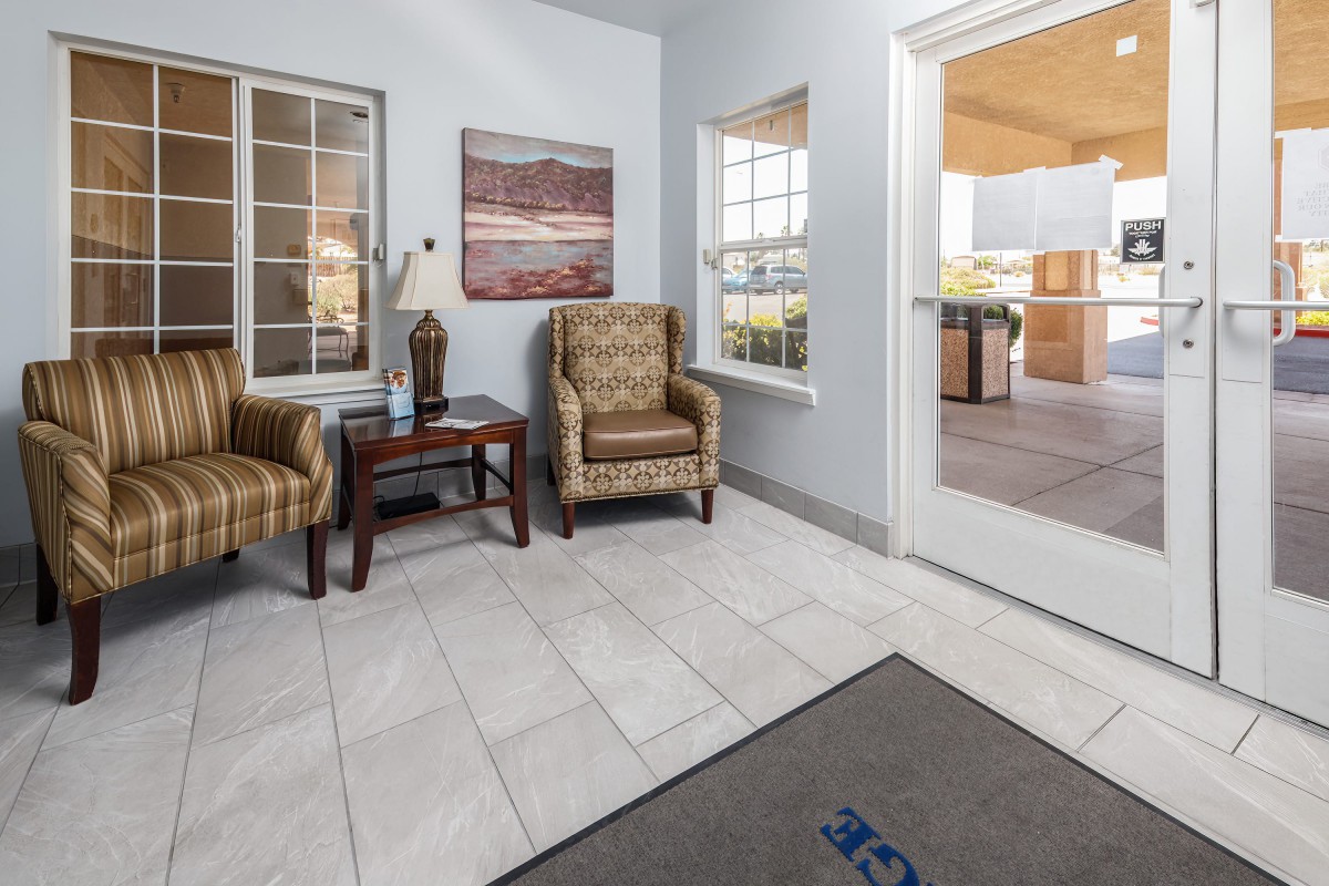 A cozy waiting area with two armchairs, a small table, decorative items, and tile flooring.