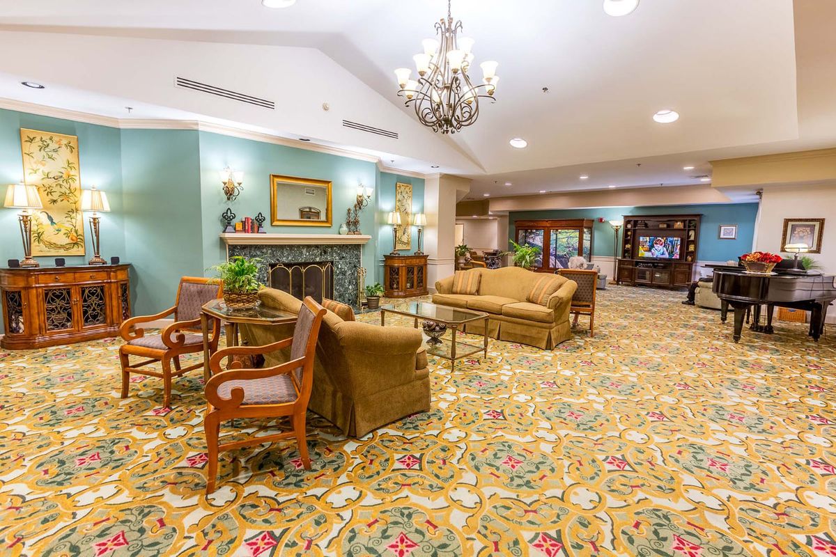 A spacious lobby with elegant furniture and a grand chandelier.