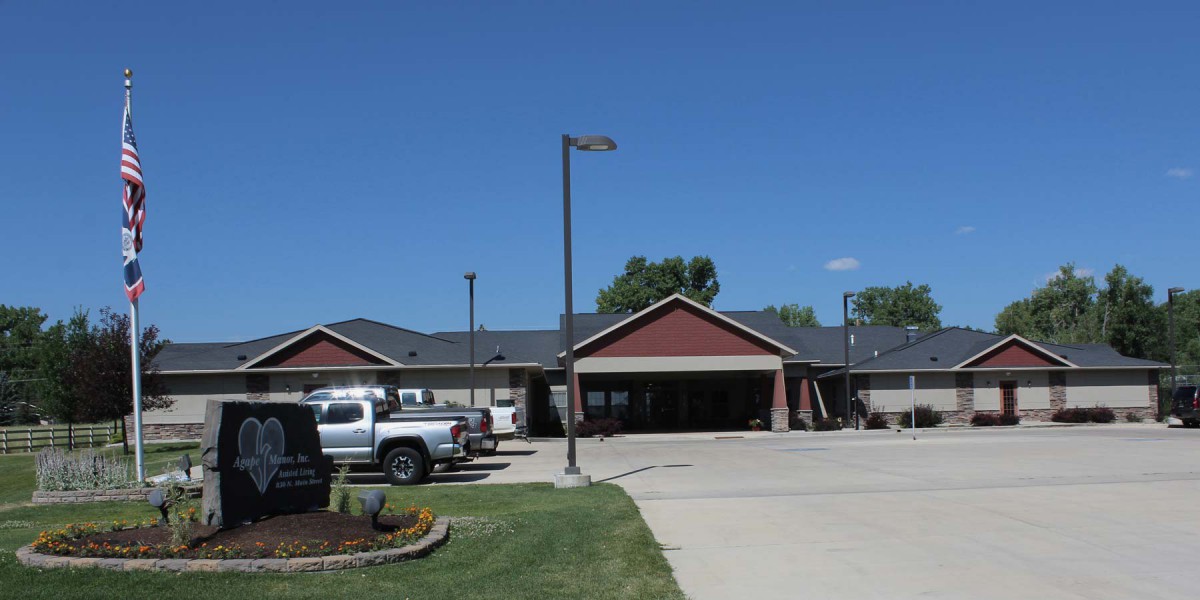 A suburban building with a parking lot and vehicles under a clear blue sky.