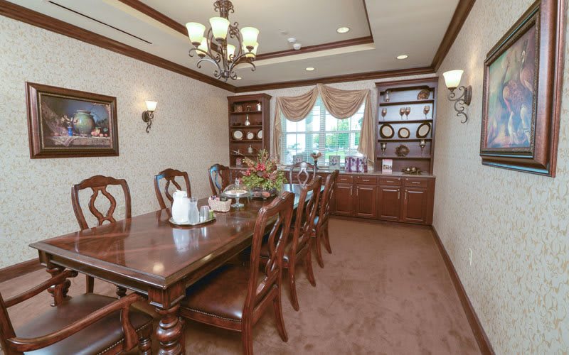 A traditional dining room with a long wooden table, matching chairs, and a decorative chandelier.
