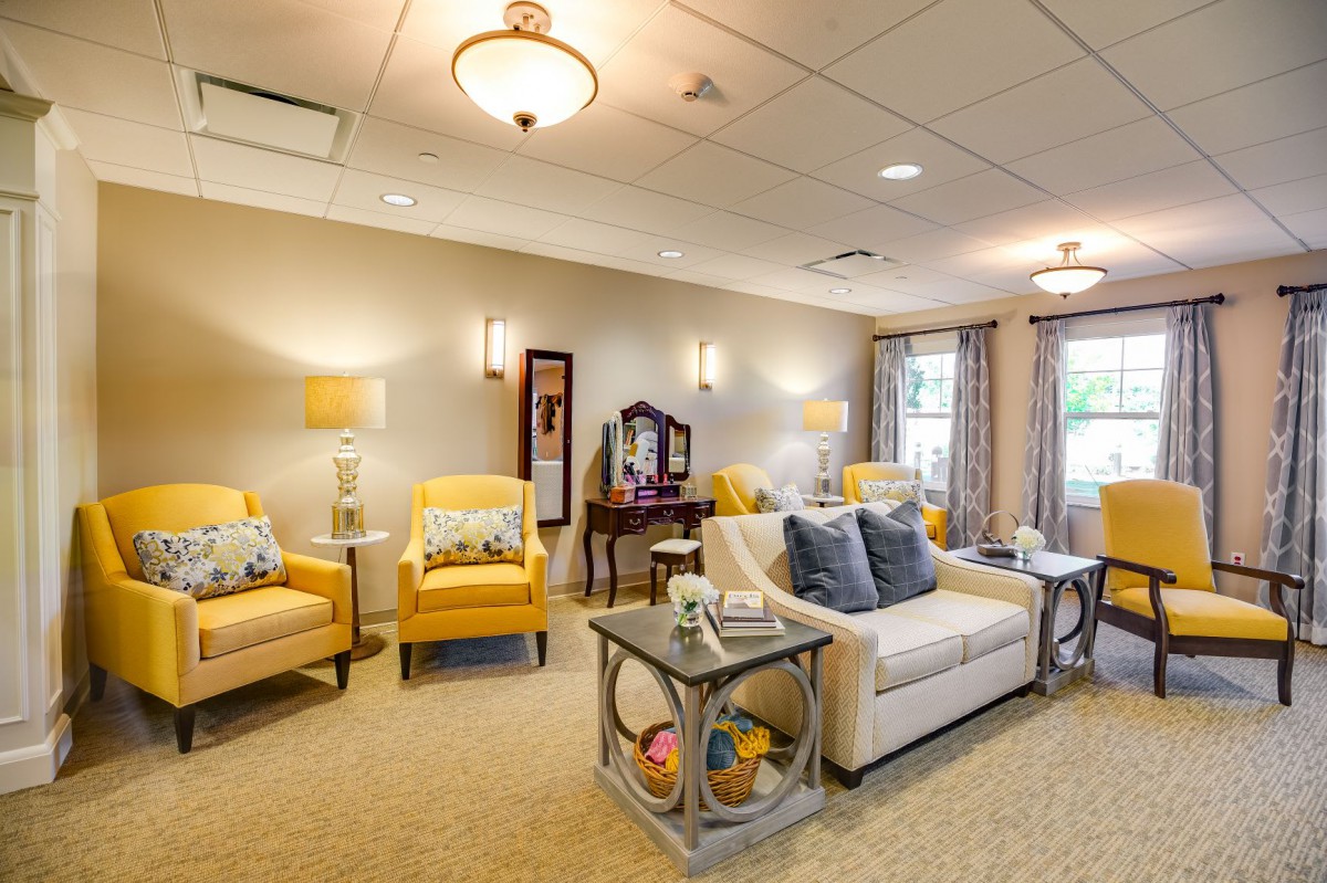 A cozy living room with yellow armchairs and a beige sofa, featuring warm lighting and elegant decor.