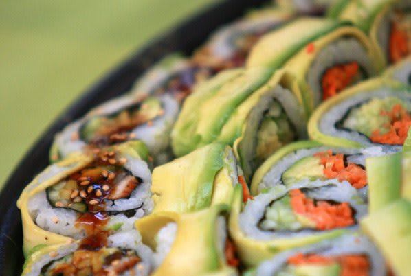 Close-up of sushi rolls topped with avocado slices.