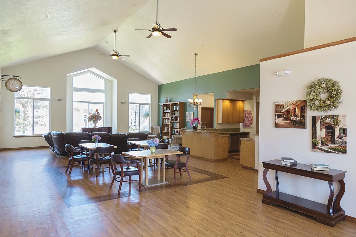 A spacious dining area with wooden tables and chairs, featuring large windows and ceiling fans.