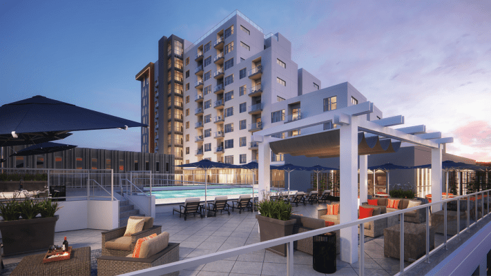 A modern apartment building with a pool area at dusk.