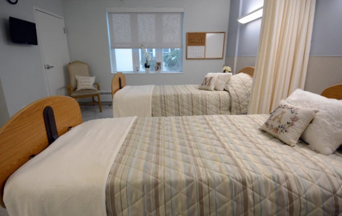A brightly lit hospital room with two neatly made beds and simple decor.