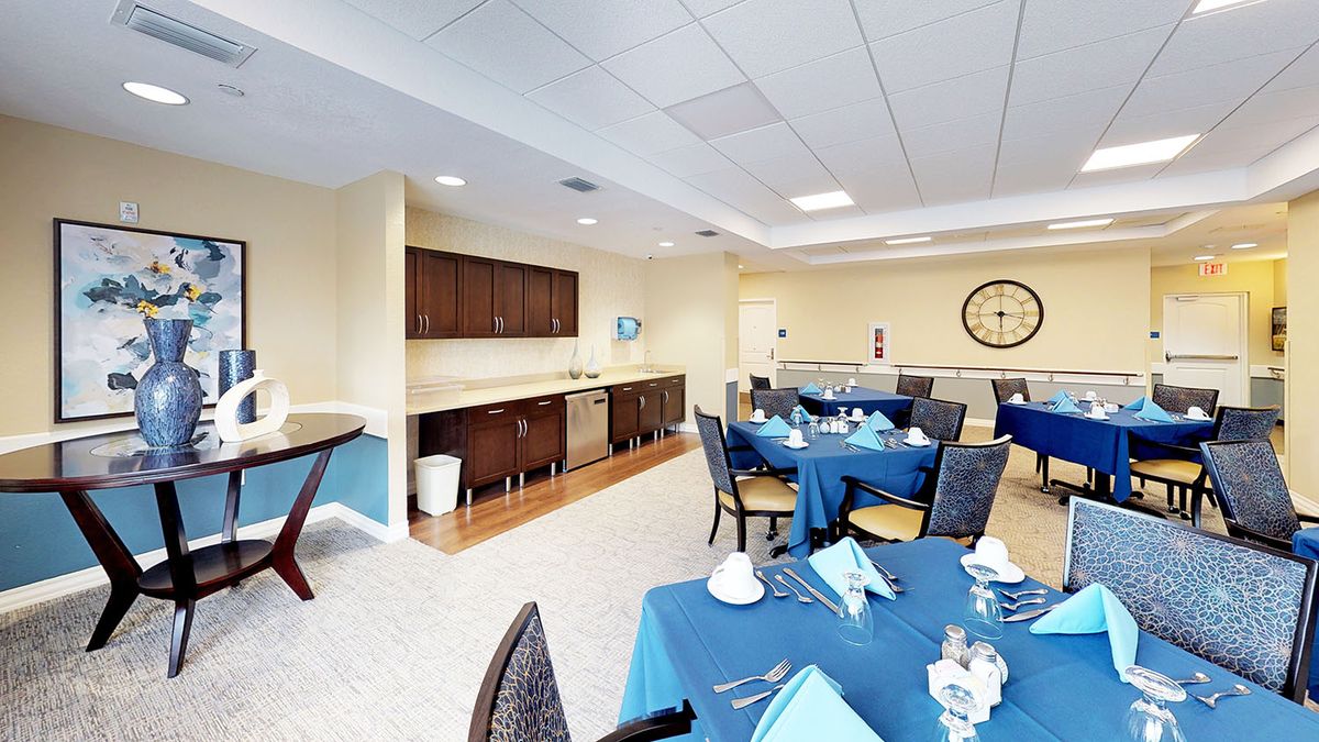 An elegantly set dining area with tables covered in blue tablecloths and neatly arranged chairs.