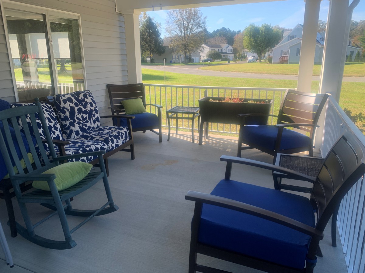 A cozy porch with various chairs and outdoor furniture on a sunny day.