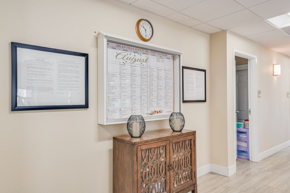 An interior view of a reception area with a notice board, clock, and decorative items on a wooden cabinet.