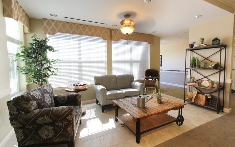 A cozy living room with comfortable seating, a wooden coffee table, and large windows allowing natural light to brighten the space.