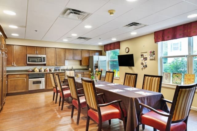 A spacious dining area with a table set for meals, adjacent to a modern kitchen.