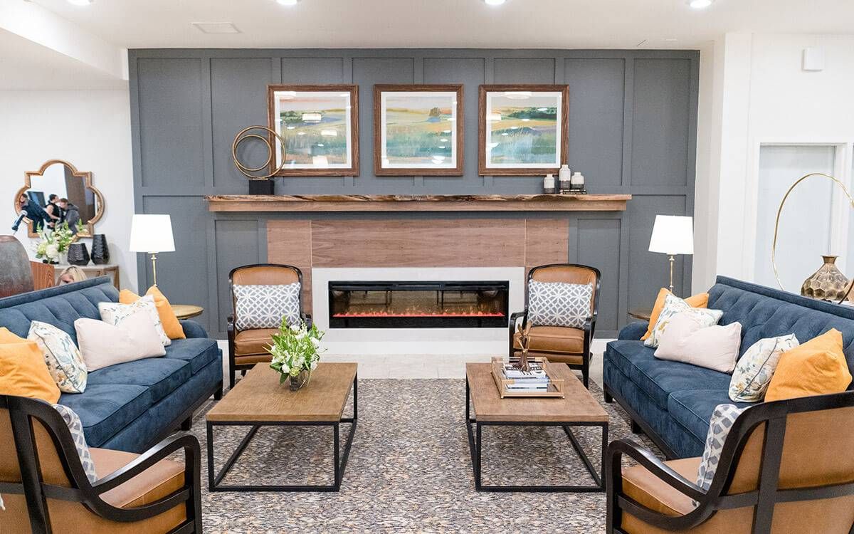 A modern living room with stylish seating and a central fireplace, accented by artwork on the walls.