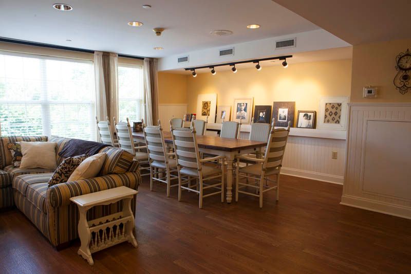 A spacious meeting room featuring a large wooden table surrounded by chairs, with an art display on the wall.