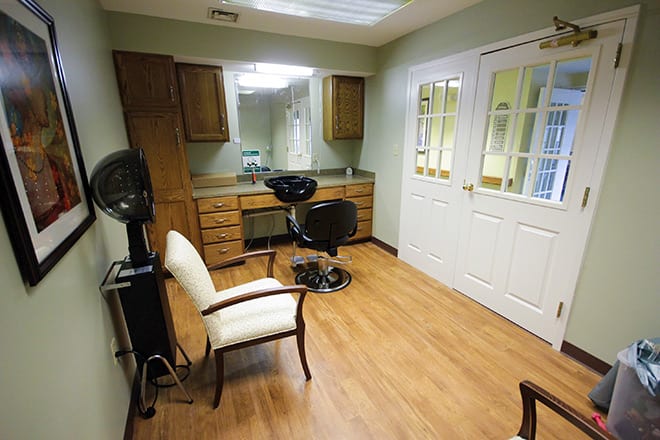 A cozy hair salon interior featuring a hairdressing station with mirrors and chairs on a wooden floor.