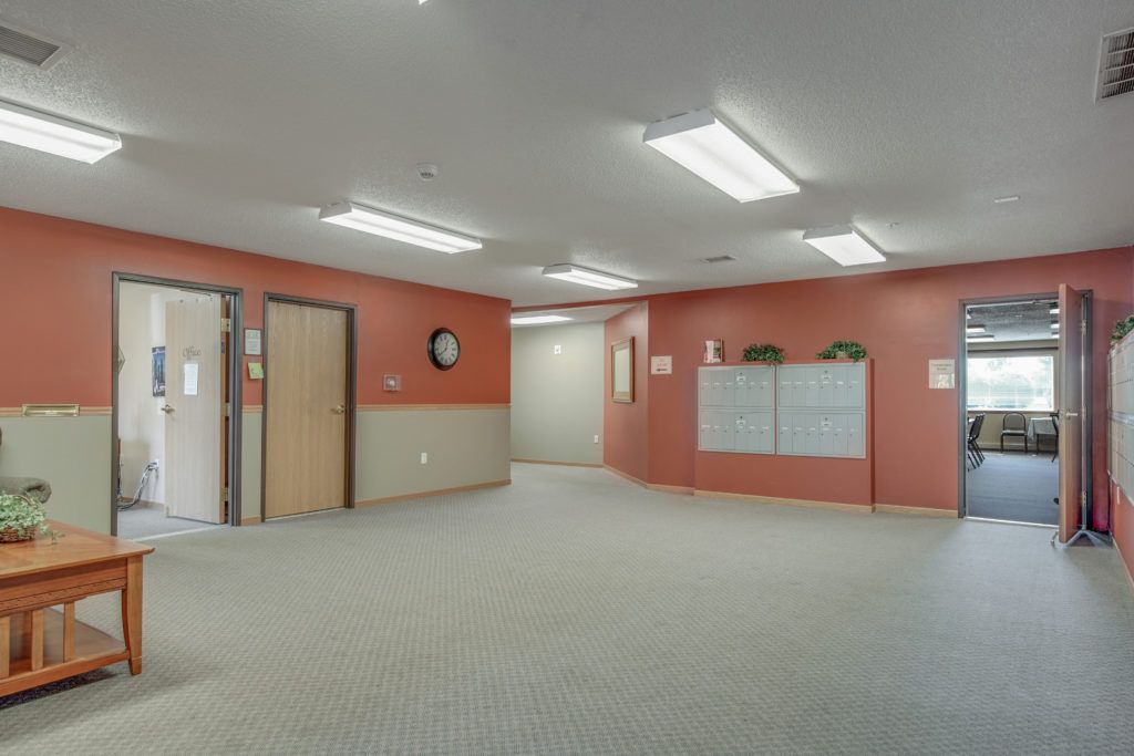 An empty hospital hallway with a reception desk and a clock on the wall.