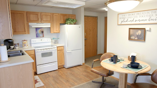 A cozy kitchen and dining area with wooden cabinets, a white refrigerator, and a round table set for a meal.