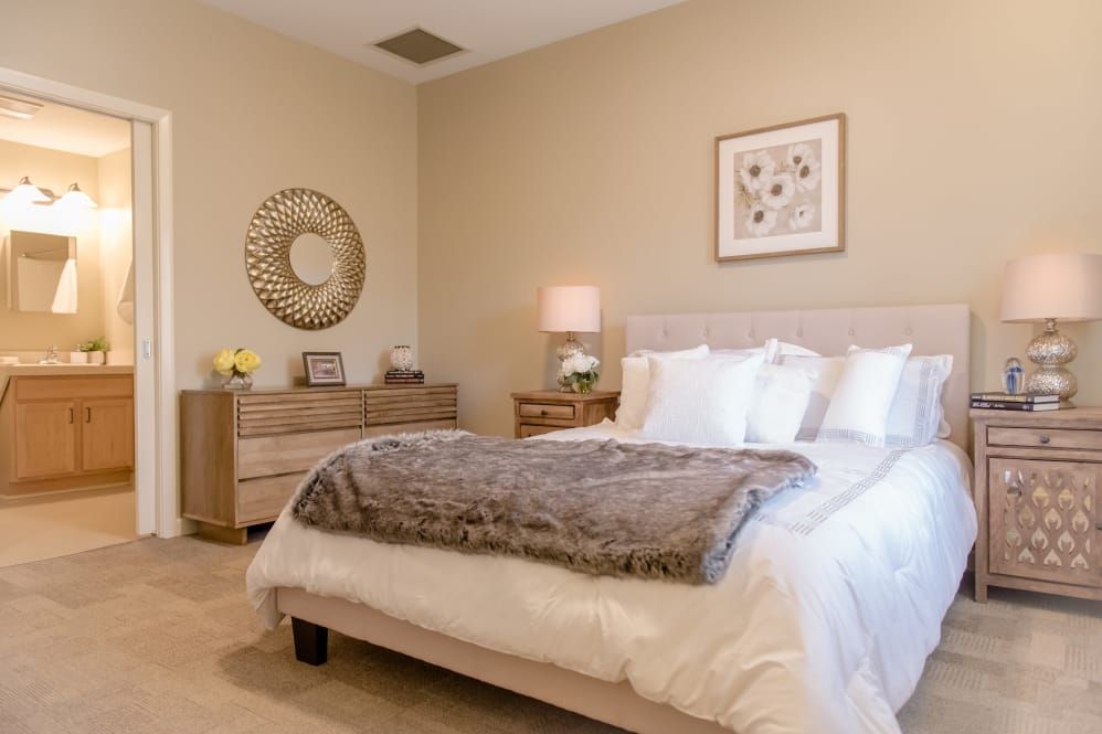 A cozy and modern bedroom featuring elegant decor with a plush bed, decorative mirror, and warm lighting.