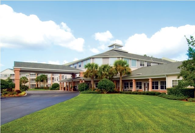 A large hotel building with a well-manicured lawn and clear skies.